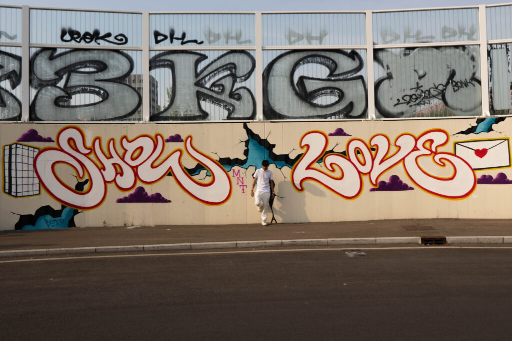 Il graffito Show Love bianco e rosso alla rotonda Bottoni, con un ragazzo appoggiato al muro